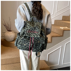 Close-up of green leopard print canvas backpack with red drawstring and embroidery