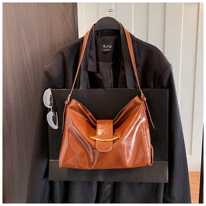 Vue détaillée du sac cabas en cuir verni marron avec boucle métallique dorée incurvée