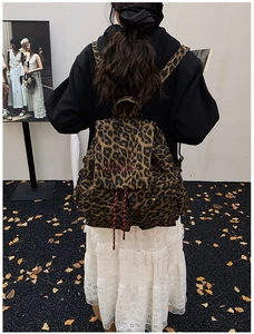 Detail of leopard print canvas backpack with red drawstring and cursive embroidery