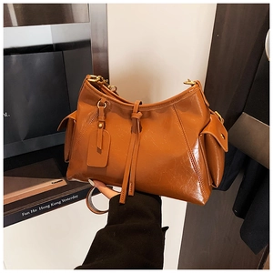 Close-up of a brown glossy leather hobo tote bag featuring side pockets and drawstrings
