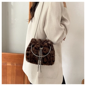 Detail of plush leopard print bucket bag with silver chain strap and metal tassel