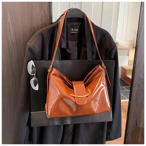 Gros plan du sac cabas marron caramel avec boucle dorée en croissant et bandoulière réglable