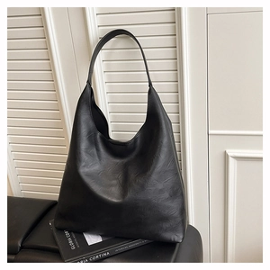 Detail of minimalist black oversized tote bag showing textured faux leather and soft hobo style