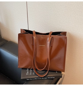 Detail einer braunen Shopper-Tasche aus Glattleder mit goldenem Schriftzug und Design