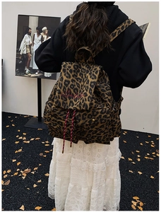 Detail of red floral embroidery and drawstring on a leopard print canvas backpack