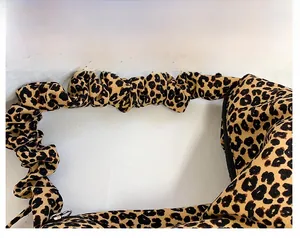 Detail showing leopard print canvas bag with pleated design and black metal zipper closure