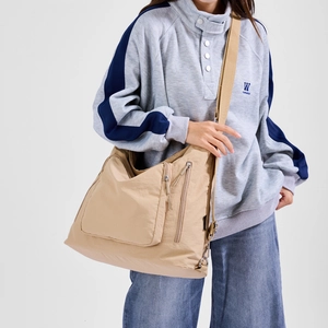 Detail view of khaki multi-pocket crossbody bag with wide strap and functional zippers