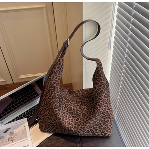 Detail of large leopard print tote bag featuring adjustable brown shoulder strap and silver buckle