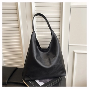 Close-up of the natural leather texture and soft folds on a large black hobo tote bag