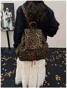 Detail of red cursive embroidery on leopard print canvas backpack with drawstring closure