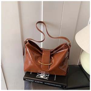 Vue détaillée du sac en cuir verni marron avec des accents métalliques dorés courbes