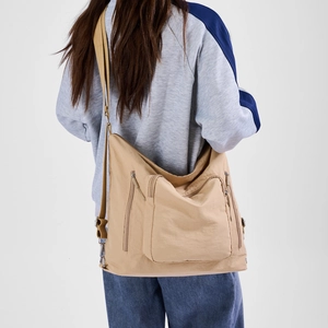 Detail view of khaki multi-pocket crossbody bag with adjustable strap on casual model