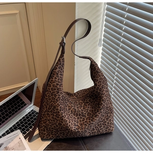 Macro view of leopard print tote bag fabric with dark brown shoulder straps and laptop