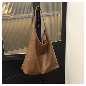 Macro view of caramel brown faux leather texture and minimalist hobo bag silhouette