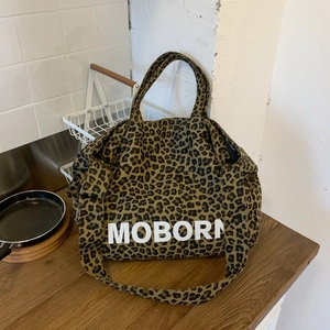 Détail du sac cabas en toile à motif léopard avec lettrage MOBORN sur une table