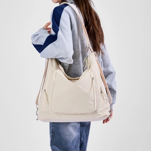 Detail of cream-white large capacity tote bag featuring multi-functional zip pockets