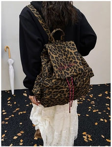 Detail shot of leopard print canvas backpack showing red embroidery and drawstring closure
