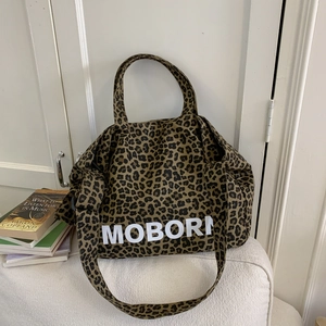Détail du cabas en toile imprimé léopard avec texte MOBORN blanc et bandoulière large