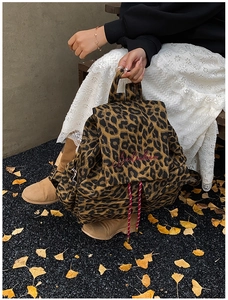 Detail of leopard print canvas backpack featuring red drawstring and floral logo embroidery
