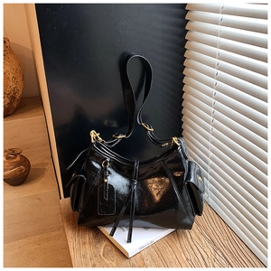 Close-up of black patent leather tote bag featuring gold hardware and side pockets