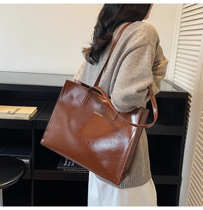 Braune Hochglanz-Tragetasche mit Fashion & Bags Text auf der Schulter getragen