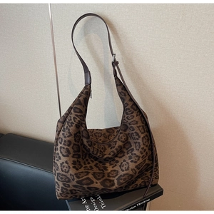 Detail of adjustable dark brown leather strap and classic leopard print canvas on hobo bag