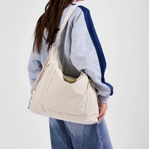 Detail of creamy white nylon crossbody bag with silver zippers and wide shoulder strap