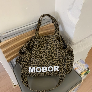 Détail du sac cabas en toile léopard avec lettrage MOBOR et poignées de transport robustes
