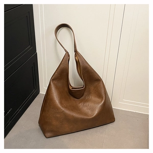 Detail shot of a brown oversized hobo bag showing textured faux leather and soft drape