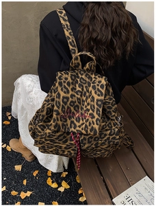 Detail of leopard print canvas backpack showing drawstring closure and red embroidery