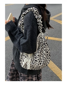 Detail of leopard print tote bag featuring pleated strap and lace pearl accessories
