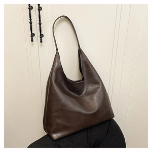 Detail shot of the deep brown glossy leather texture and spacious shoulder bag design