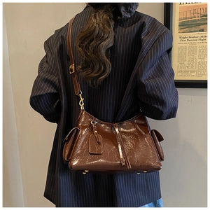 Deep brown oil-wax leather tote bag shown on model with side flap pockets and vintage gold hardware