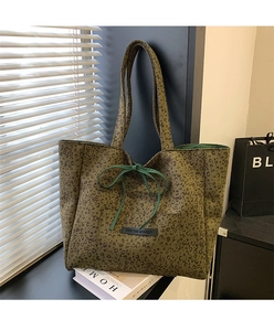 Close-up of leopard print tote bag with bow detail and Own The Moment patch