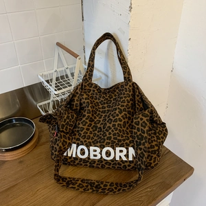 Détail du grand sac cabas en toile à imprimé léopard avec logo MOBORN blanc et bandoulière