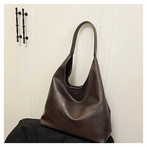 Macro detail of dark brown soft faux leather hobo tote bag with a smooth polished texture