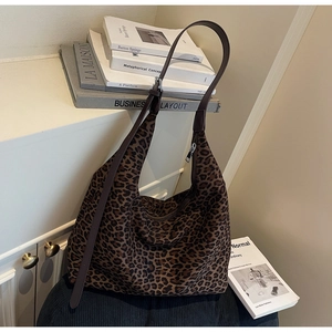 Detail of leopard print tote bag featuring brown leather strap and silver buckle hardware