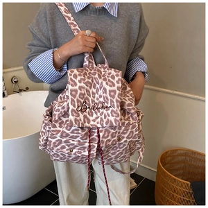 Detail of leopard print canvas backpack showing the drawstring closure and embroidery