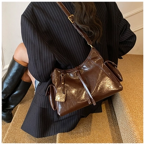Detail of a shiny chocolate brown tote bag with side pockets and adjustable strap