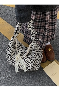 Detail of leopard print tote bag featuring a scrunchie handle and lace pearl charm