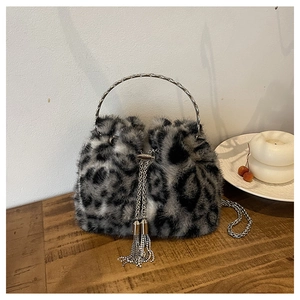 Detail of leopard print plush bucket bag with metal handle and chain strap on wood table