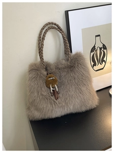 Detail of soft faux fur tote with braided handles and plush charm on a minimal desk