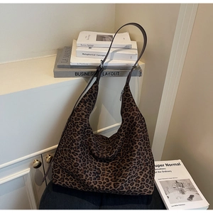 Detail of high-capacity leopard print tote bag with brown leather strap and silver zipper