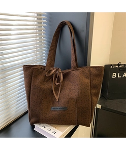 Detailed close-up of leopard print suede tote bag with decorative bow and brand label