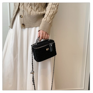 Close-up of black quilted velvet box bag with silver chain and metal ball detail