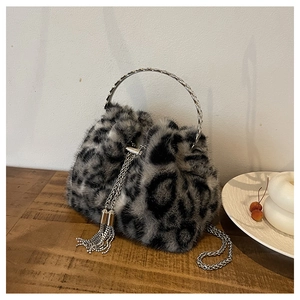 Detailed close-up of leopard print faux fur bucket bag with silver metal handle and fringe