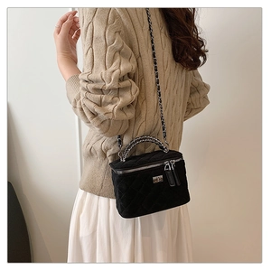 Detail of black quilted velvet crossbody bag with silver chain strap and metal lock