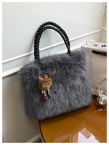 Detail of dark gray faux fur tote with woven leather handles and plush animal charm