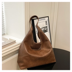 Detail of a large brown leather tote bag with soft texture on a stylish studio table