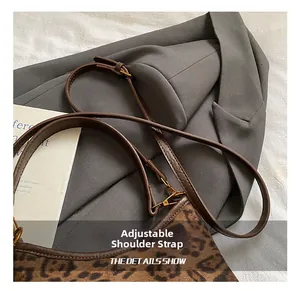 Detail of adjustable brown leather strap and gold buckle on leopard print tote bag